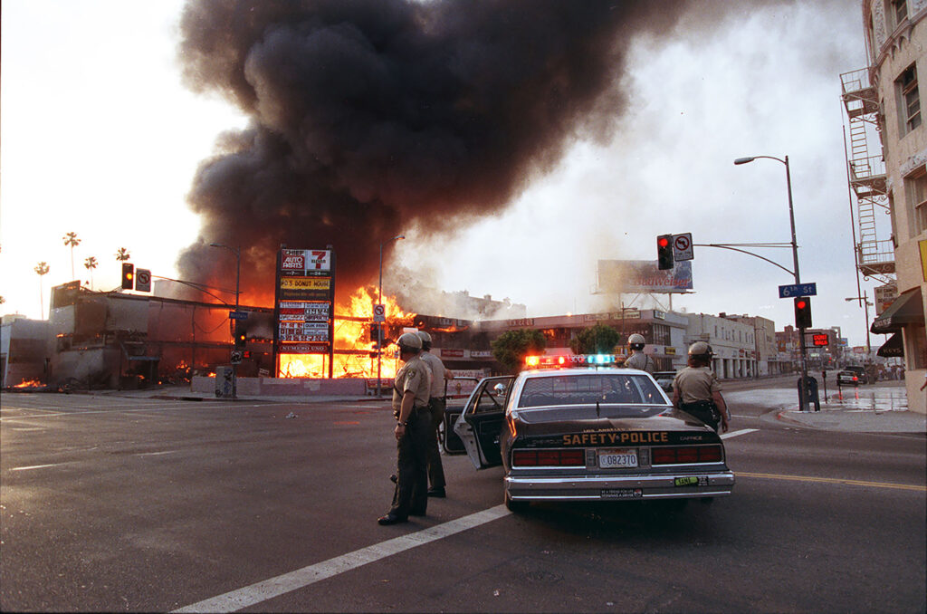 Police officers guard an intersection where a corner shopping center was set ablaze